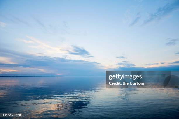 dramatic sky and dark clouds by the sea, clouds are reflected in the smooth water - 空気感 ストックフォトと画像