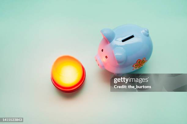 piggy bank and illuminated lamp on green background, save energy costs - energy bill stock pictures, royalty-free photos & images