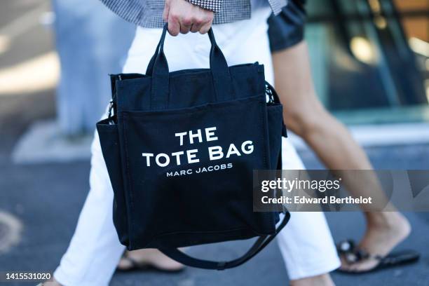 Guest wears a black and white houndstooth print pattern blazer jacket, white denim pants, a black large The Tote Bag handbag from Marc Jacobs,...