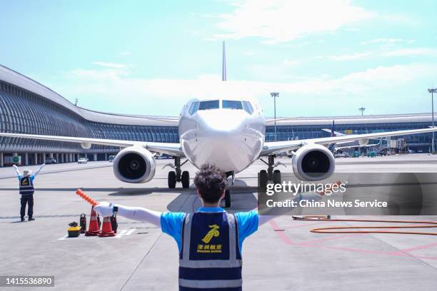 Staff member guides an aircraft into position at Nanning Wuxu International Airport during the summer travel rush on August 17, 2022 in Nanning,...