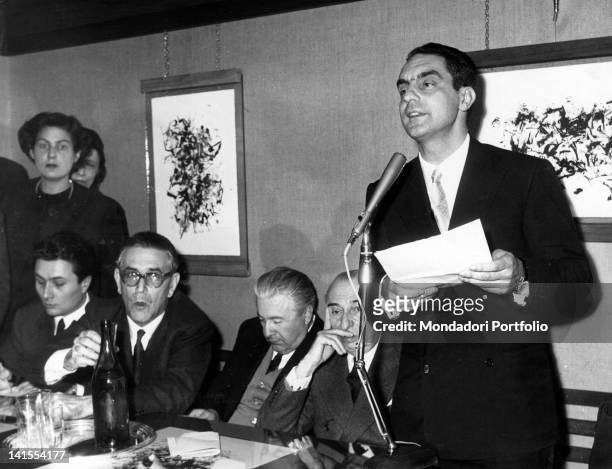 The Italian writer Italo Calvino speaking into a microphone next to the writers Alberto Arbasino, Mario Soldati e Carlo Muscetta. 1960s