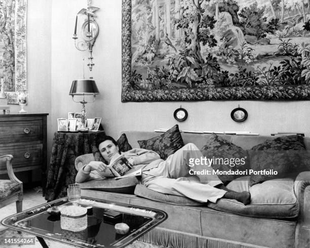 Alberto Arbasino, Italian writer, essayist and journalist, reading while lying on a couch