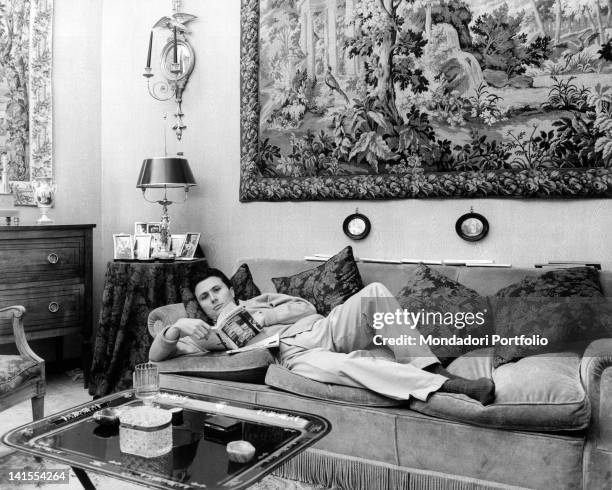 Alberto Arbasino, Italian writer, essayist and journalist, reading while lying on a couch