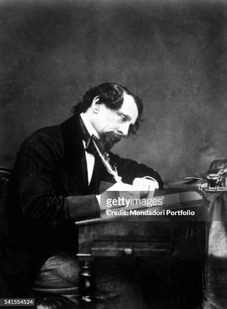 English writer Charles Dickens writing at his desk. 1860s