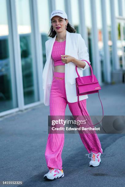 Guest wears a white with black embroidered slogan "Early Retirement" cap, earrings, a pink square print pattern cropped top, matching pink square...