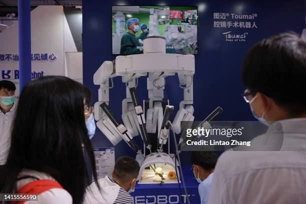 Staff member shows an intelligent robotic arm for surgery during 2022 World Robot Conference at Beijing Etrong International Exhibition on August 18,...