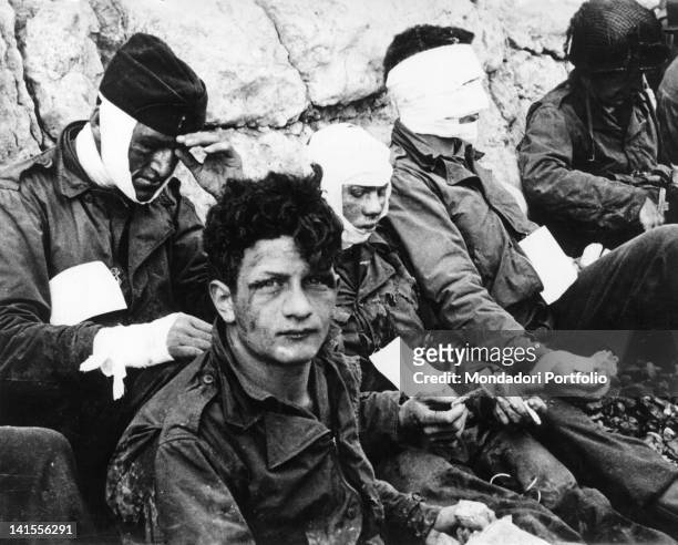 Group of U.S. Wounded soldiers sheltering behind a wall after the Normandy landing on the beach called Omaha Beach in code. Normandy, 6 June 1944