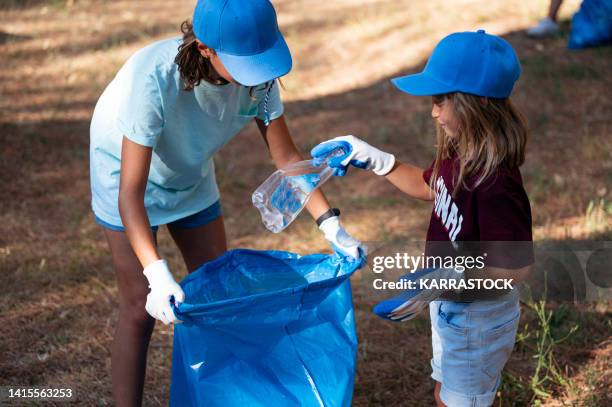 volunteer children collecting garbage in a park. - littering stock pictures, royalty-free photos & images