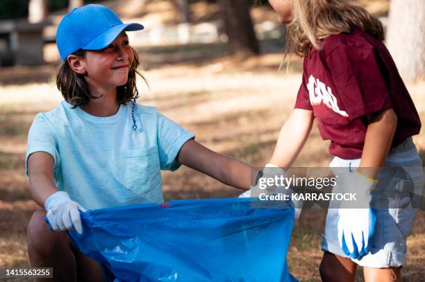 volunteer children collecting garbage in a park. - global citizen together at home stock pictures, royalty-free photos & images