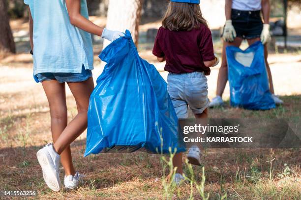 volunteer children collecting garbage in a park. - global citizen together at home stock pictures, royalty-free photos & images