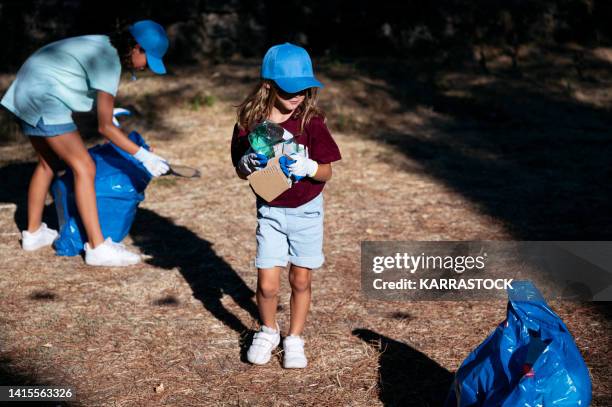 volunteer children collecting garbage in a park. - global citizen together at home stock pictures, royalty-free photos & images