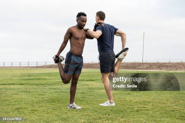 two men leaning on each other while stretching - masculinity stock pictures, royalty-free photos & images