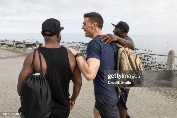 three happy friends laughing on promenade - man wearing cap photos et images de collection