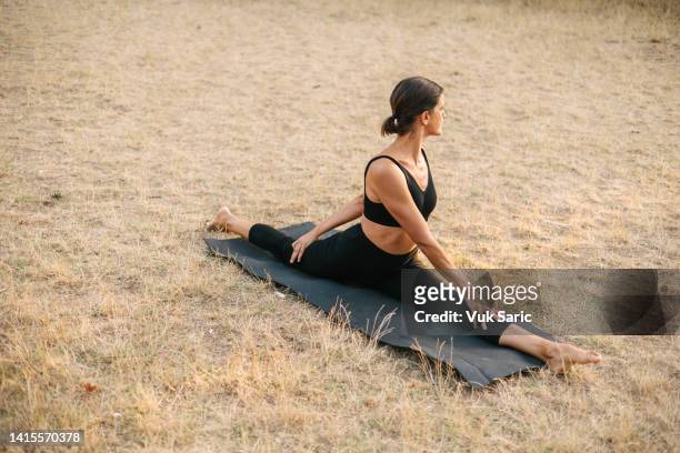 yogalehrer, der die splits auf einer wiese bei sonnenuntergang macht - spagat stock-fotos und bilder