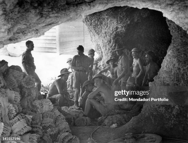 Australian soldiers in a cave during the bombardment of Tobruk; in the foreground, there are projectiles stacked in containers. Tobruk, Libya, July...