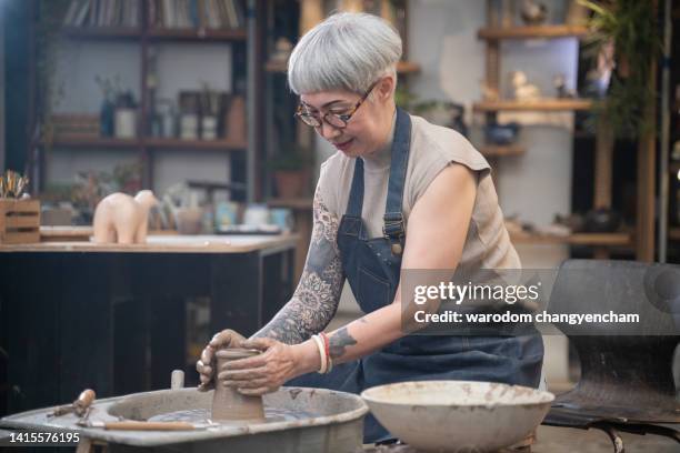 senior woman kneading clay in bowl shape at workshop. - pottery making stock pictures, royalty-free photos & images
