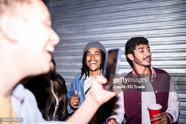 man filming or taking photos of friends enjoying nightlife - city life photos stock pictures, royalty-free photos & images