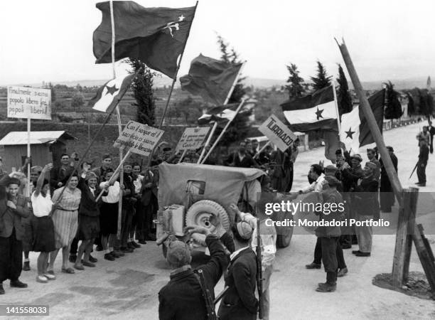 Local people waving flags and signs to a British jeep directed to Trieste passing by. Pieris, San Canzian d'Isonzo, May 1945