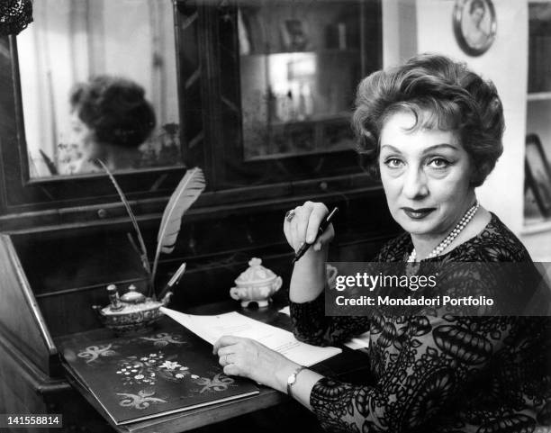 The Italian actress Andreina Pagnani writing a letter sitting on the desk. 1970s