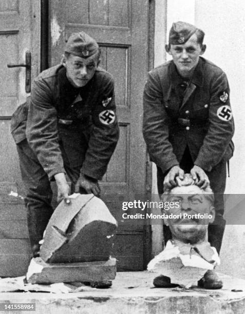Two German soldiers showing a decapitated bust of Stalin outside a house in Smolensk. Smolensk, July 1941