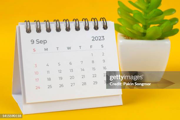 calendar desk 2023 september is the month for the organizer to plan and deadline with house plants on the table against a yellow background. - septiembre fotografías e imágenes de stock