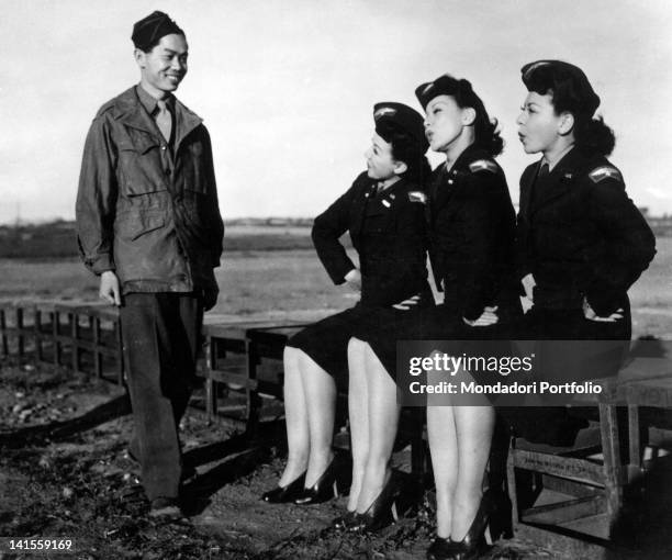 The Kim Loo sisters in auxiliary uniform joking with an Oriental airman during a stop for a show at a base of the U.S. 15th Air Force. Italy, October...