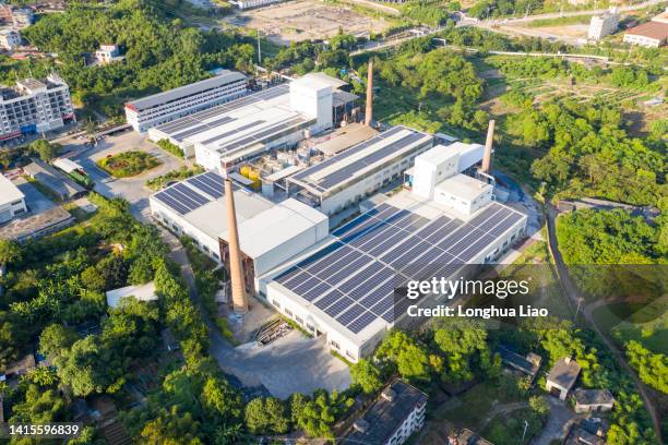 the roof of the factory is covered with solar photovoltaic panels - industrial plant outside stock pictures, royalty-free photos & images