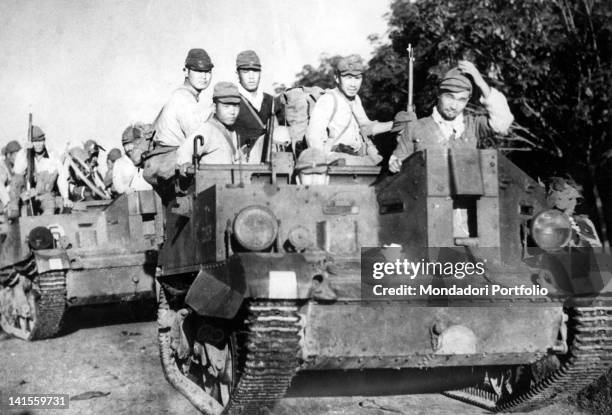 Group of Japanese soldiers advancing in the Johor region on two tanks conquered from the British. Malaysia, January 1942