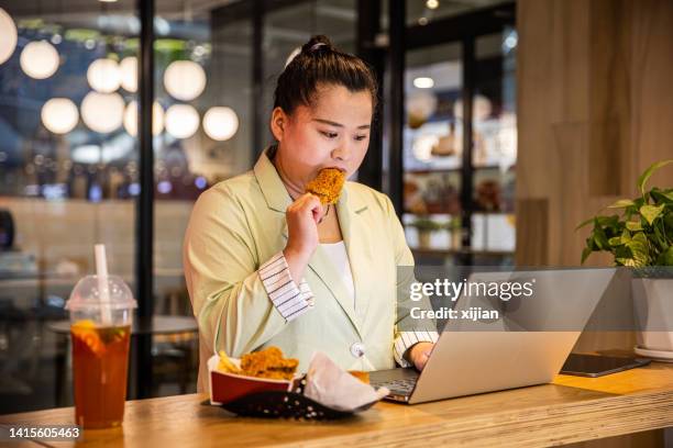 businesswoman eating fried chicken while working with laptop - stress eating stock pictures, royalty-free photos & images