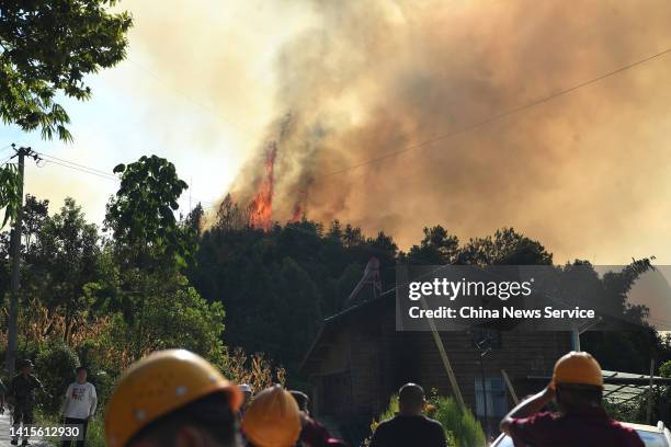 Smoke and flames rise from a hill during a forest fire on August 18, 2022 in Chongqing, China. The fire erupted on Wednesday afternoon in Nanchuan...