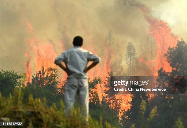 Smoke and flames rise from a hill during a forest fire on August 18, 2022 in Chongqing, China. The fire erupted on Wednesday afternoon in Nanchuan...