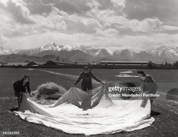 Man and two women of a partisan division lay down a white sheet as a signal for allied aircrafts supposed to supply provisions. Italy, April 1945,...