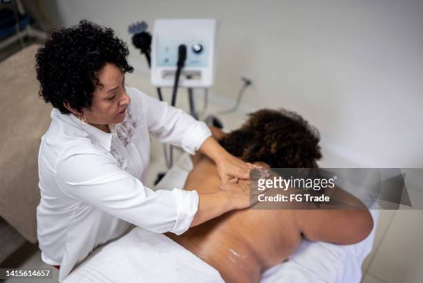 kosmetikerin massiert einen kunden in einem beauty-spa - liposuction stock-fotos und bilder