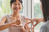 Young attractive Asian women using sign hand finger language conversation with deaf person. Cheerful happy using nonverbal communication to persons with disabilities.