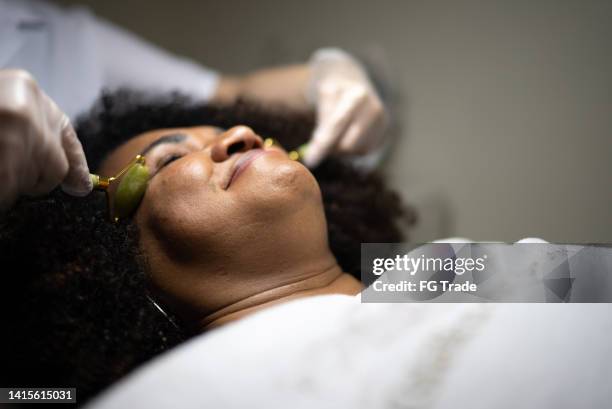 mature woman receiving massage with gemstone rollers at beauty spa - semi precious gem stock pictures, royalty-free photos & images