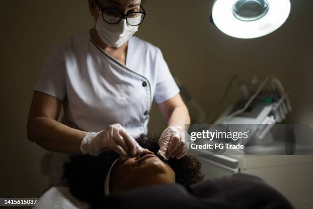 esteticista limpiando la piel del cliente en un spa - esteticista fotografías e imágenes de stock