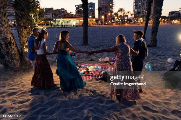 multigeneration family having summer picnic party on the beach - night picnic stock pictures, royalty-free photos & images