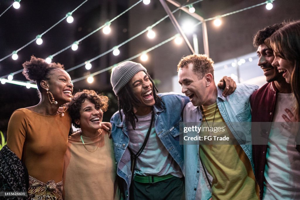 Friends embracing having fun in the street at night