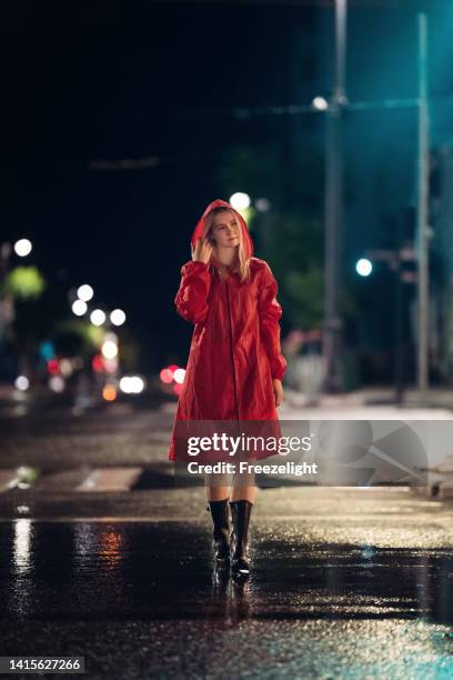 young lady in red raincoat under a traffic light - standing water stockfoto's en -beelden