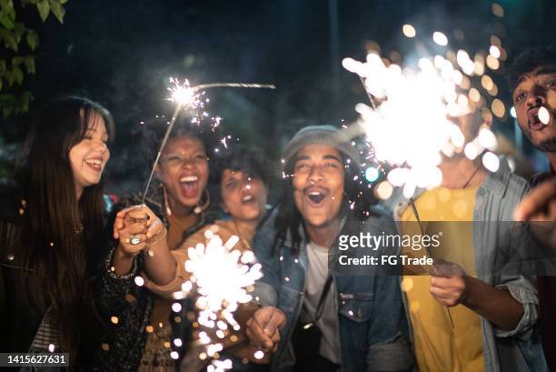 amigos celebrando con bengalas en la calle por la noche - reencuentro fotografías e imágenes de stock