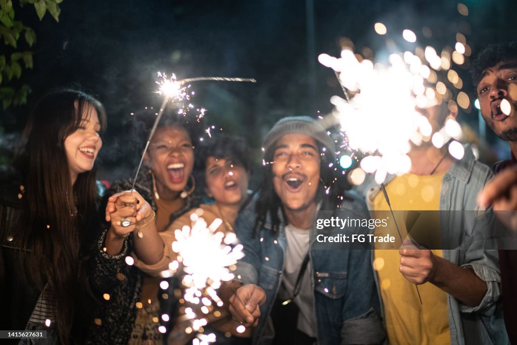 Amici che festeggiano con scintille in strada di notte