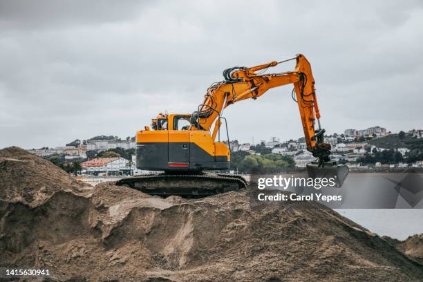 excavation machine working at the seaside with sand - grävmaskin bildbanksfoton och bilder