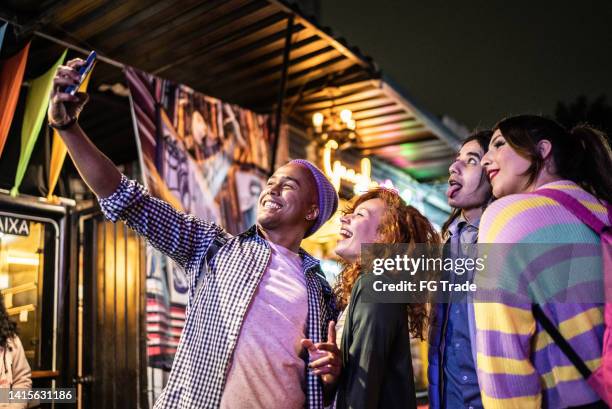 friends taking selfies or filming using mobile phone outdoors at festival by the night - including a transgender person - festival de film bildbanksfoton och bilder