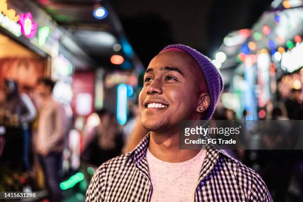young man walking and looking around at music festival by the night - film festival stock pictures, royalty-free photos & images