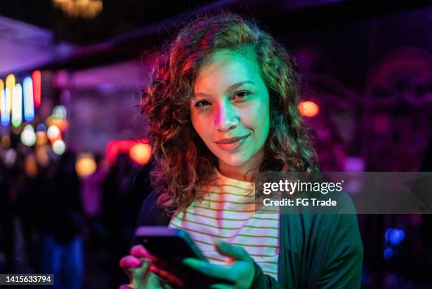 portrait of a young woman using the mobile phone at nightlife - music festival phone stock pictures, royalty-free photos & images