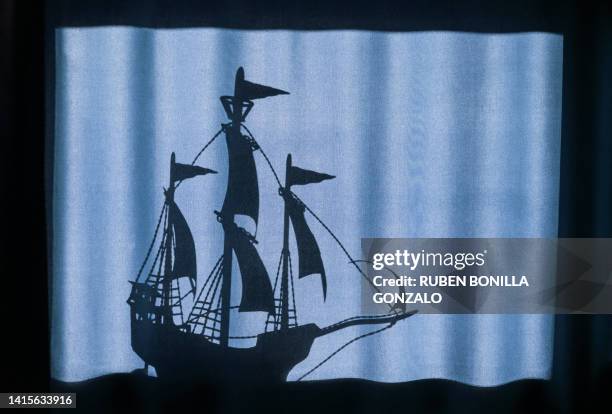 side view of a sailing ship in dark silhouette creating shadow on a blue curtain in a frame. art concept. - clippers stock pictures, royalty-free photos & images