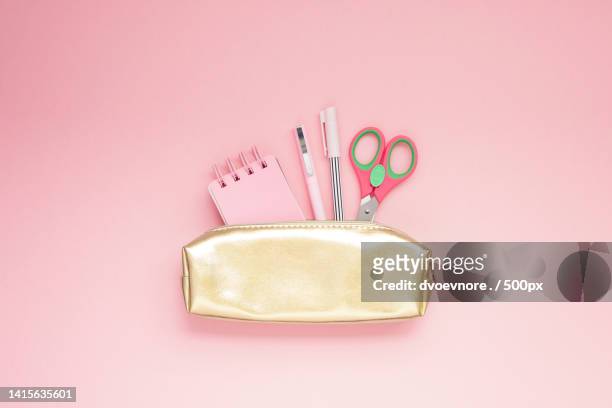 directly above shot of scissors and office supplies in purse on pink background - trousse d'écolier photos et images de collection