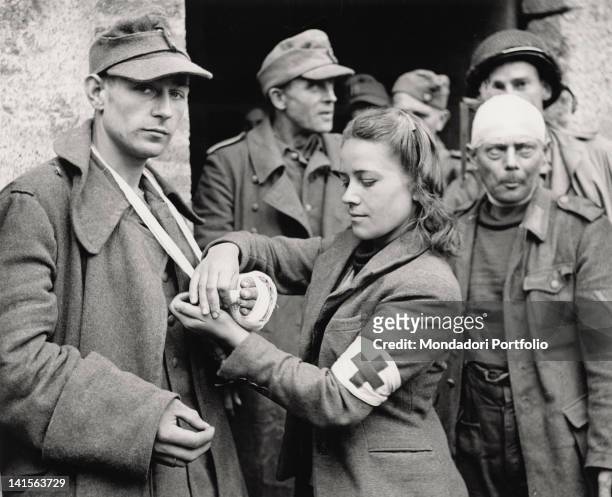 German member of the Women's Army Auxiliary Corps, taken prisoner together with the men of the Cherbourg garrison, in Lower Normandy, treats the...