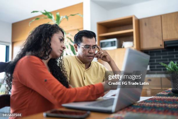 worried couple using laptop doing home finances - stress test stockfoto's en -beelden