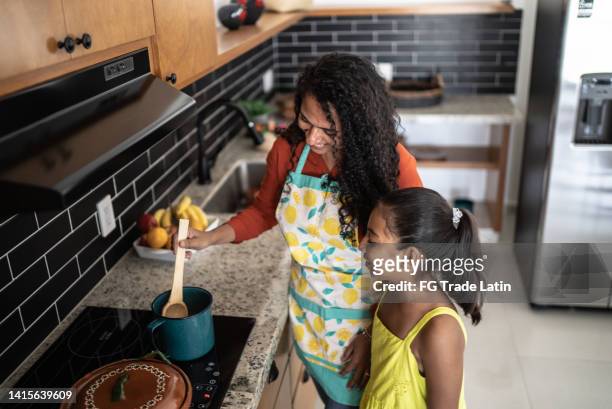 mother and daughter cooking at home - hot latino girl imagens e fotografias de stock